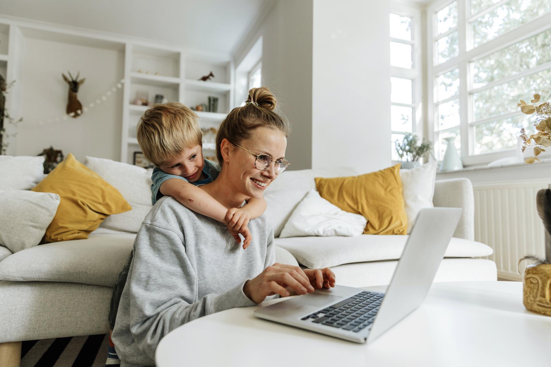 Mamma och barn använder en dator tillsammans i vardagsrummet